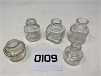5 different clear inkwells.