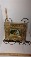brass colored book/ art stand with framed print