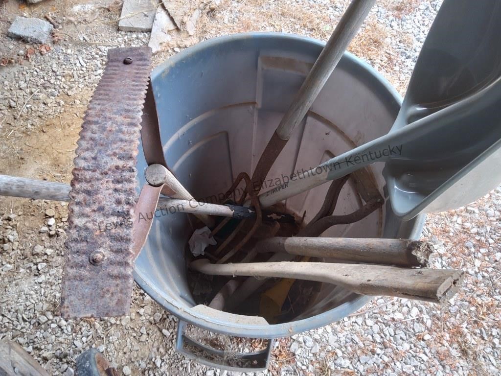 Trash can with yard utensils in bad repair some