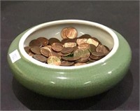 Glazed ceramic bowl filled with pennies - appears
