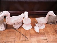 Four concrete geese yard ornaments: three are