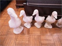 Four concrete yard geese ornaments: three are