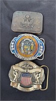 Three different centennial belt buckles