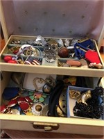 Tan box of costume jewelry with many awards