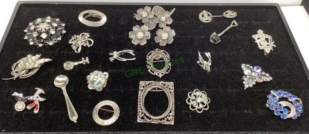 Lot includes silver tone brooches and pins .