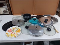 Assorted glass and metal lids, plate, knife, pan