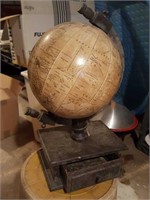 World globe sitting on wood stand with one drawer