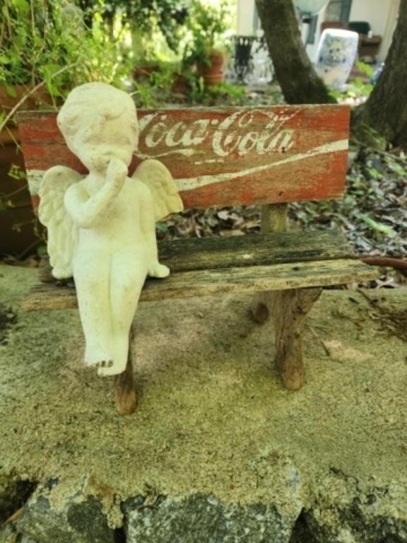 Ceramic angel on antique coca cola bench