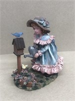 Girl watering flowers with bird house