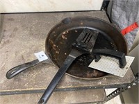 Black cast iron skillet, spatula, hand press