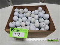 Box of many used golf balls; various brands