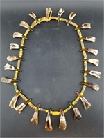 Necklace made with aged buffalo's teeth and old st