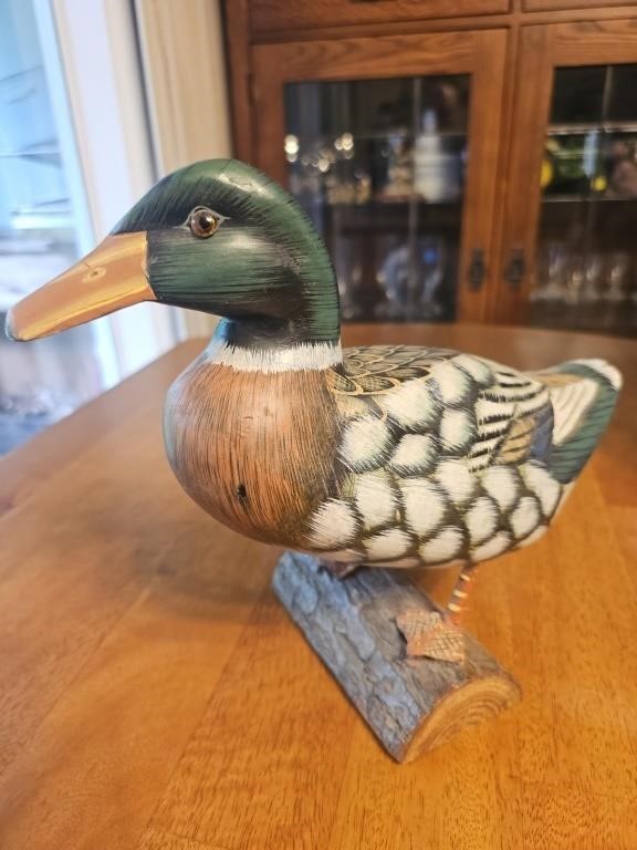 Vintage wood mallard duck standing on log