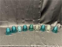 Nine glass insulators, four blue, one is green, on