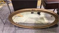 Antique oval wall mirror with ornate frame and