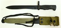 Black military knife in green sheath