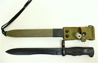 Black military knife in green sheath