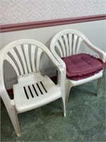 2 white plastic lawn chairs with pink cushions