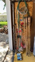 Tiki torches, yard tool handles, hose, and reel,