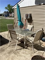 Glass patio table with four chairs and umbrella