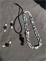 Three necklaces one with blue and white beads