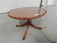Oval shaped coffee table with glass on top and cla