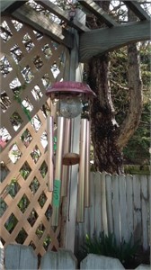 Metal wind chime hanging on arch in backyard