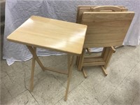 Set of four wooden portable TV trays in a stand.