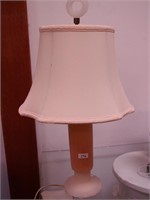 An opaque boudoir lamp painted orange and cream