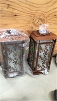 Two copper tone table lanterns with leaf branch