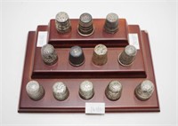 Twelve various vintage thimbles on a timber stand