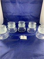 Five small clear glass jars with lids