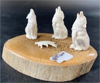 Bone carving of howling wolves, circling around a