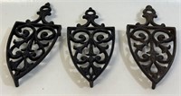 TWO ORNATE CAST SAD IRON FOOTED TRIVETS