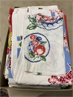 Box full of printed vintage table cloths