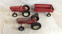 Two red toy tractors and red toy trailer