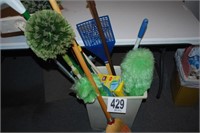 TRASH CAN FULL OF DUSTERS, BROOMS, DUSTPANS &