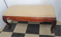 Wood bench with claw feet and upholstered seat.