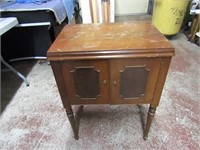 Singer sewing machine in wood cabinet.