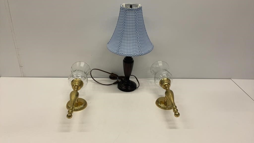Two brass toned candle sconces and a lamp with