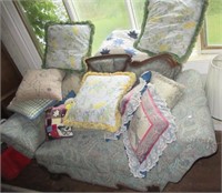 Vintage loveseat with various pillows and quilt.