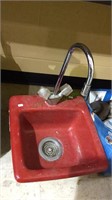 Small red fiberglass sink with the spigot and