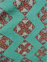Green quilt with floral pattern.