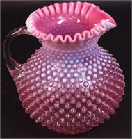 An opalescent to pink hobnail water pitcher with