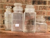 Four Apothecary Jars with lids one is chipped