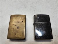 Brass Zippo and dark chrome Zippo lighters.