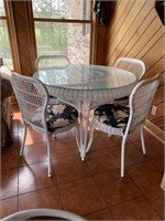 Round white wicker table with glass top and