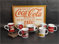 Variety of Coca Cola Mugs, A Cup Warmer, and Frame