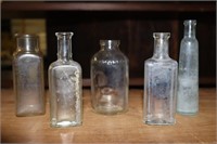 Group of Clear Glass Medicine Bottles One Marked