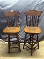 Oak cane seated swivel bar stool pair with carved
